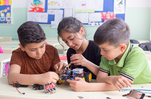 Three children working together to build something out of mechanical pieces.