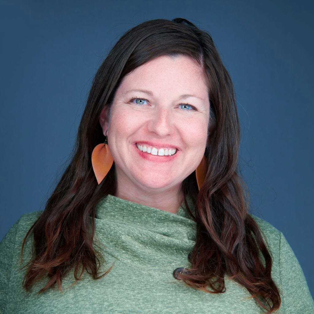 Image of a white woman with long dark brown hair, blue eyes and a pale green shirt. 