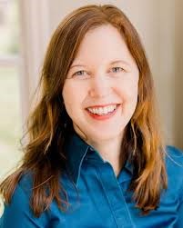 Image of a smiling woman with long golden brown hair wearing a blue shirt. 