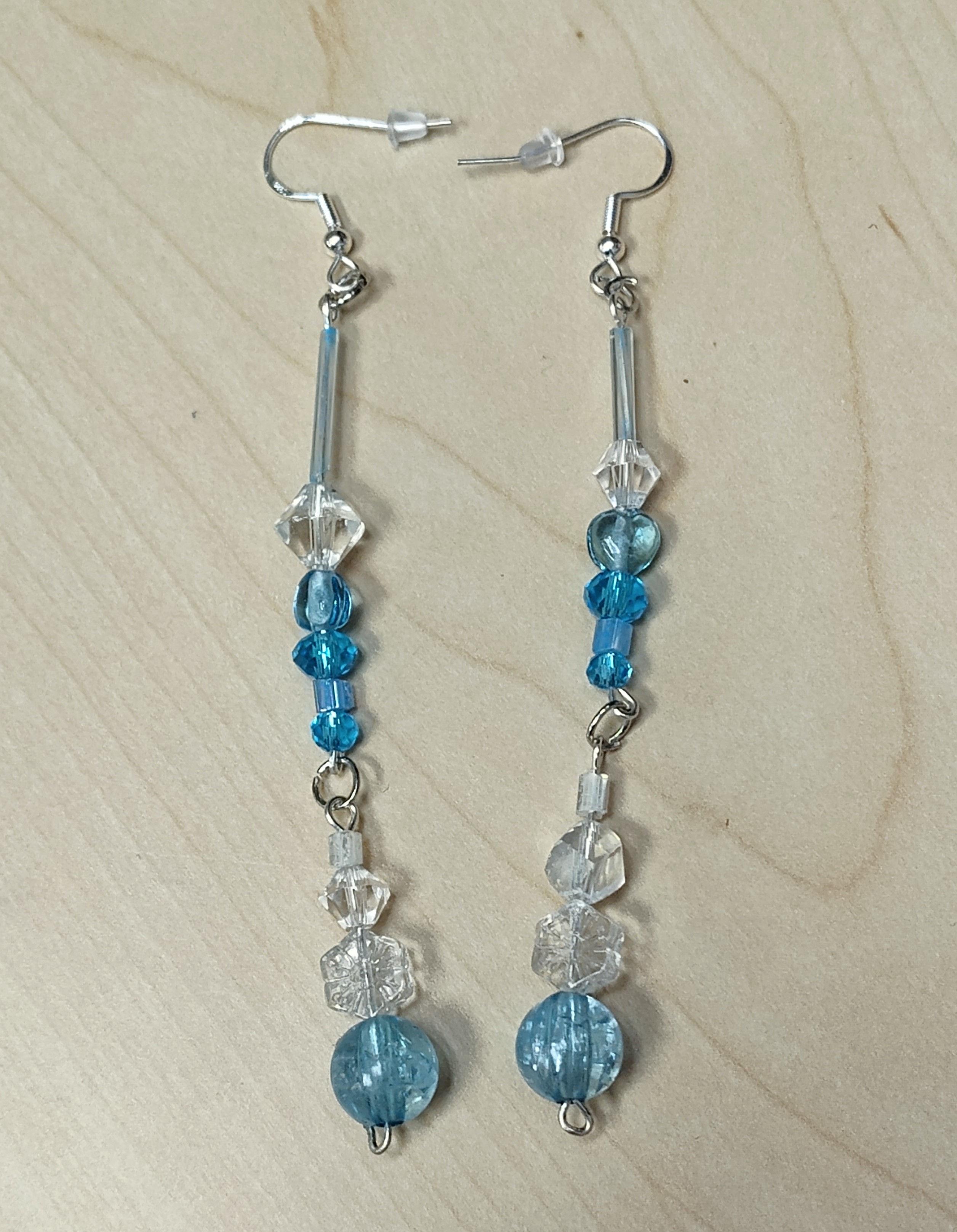 A pair of frost themed dangly earrings, in translucent blue and white.