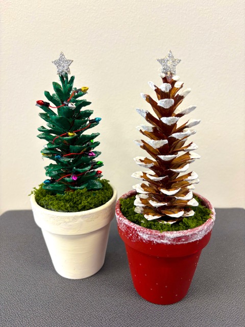 Photo of two pots with pinecones in them that are decorated to look like Christmas trees
