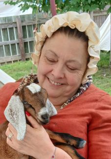 woman in revolutionary time clothing holding a lamb
