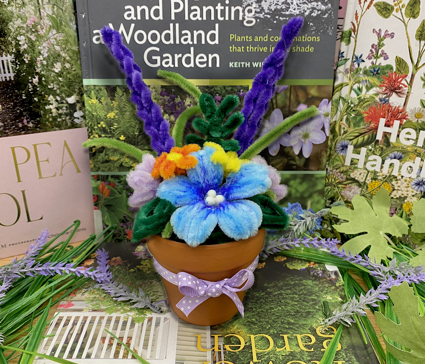 Various flowers created out of pipe cleaners in a ceramic pot