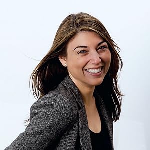 Image of a smiling woman with long dark brown hair wearing a black shirt and a dark grey jacket. 