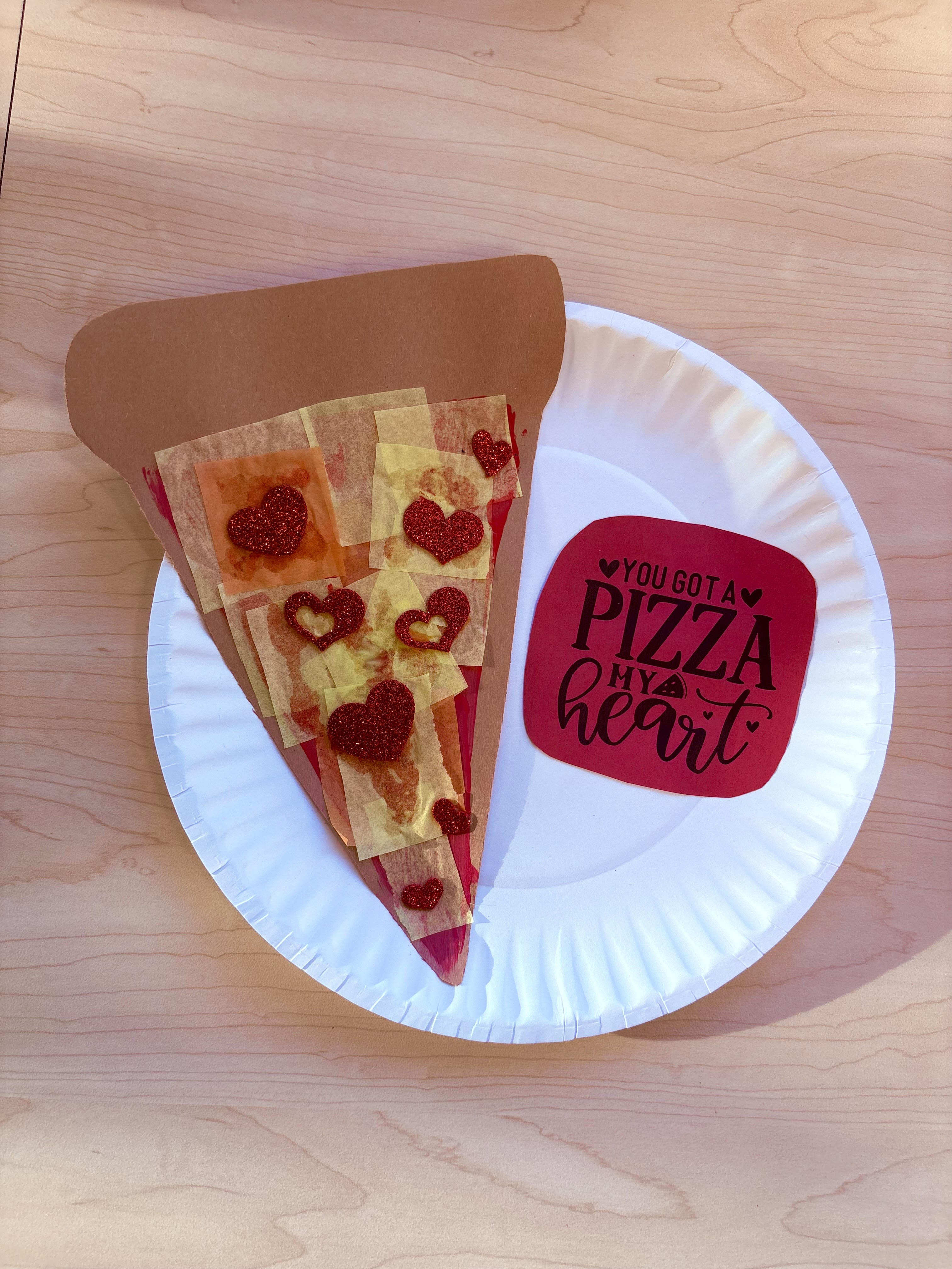Plate with construction paper slice of pizza with red heart sticker pepperonis that says "YOU GOT A PIZZA MY HEART"