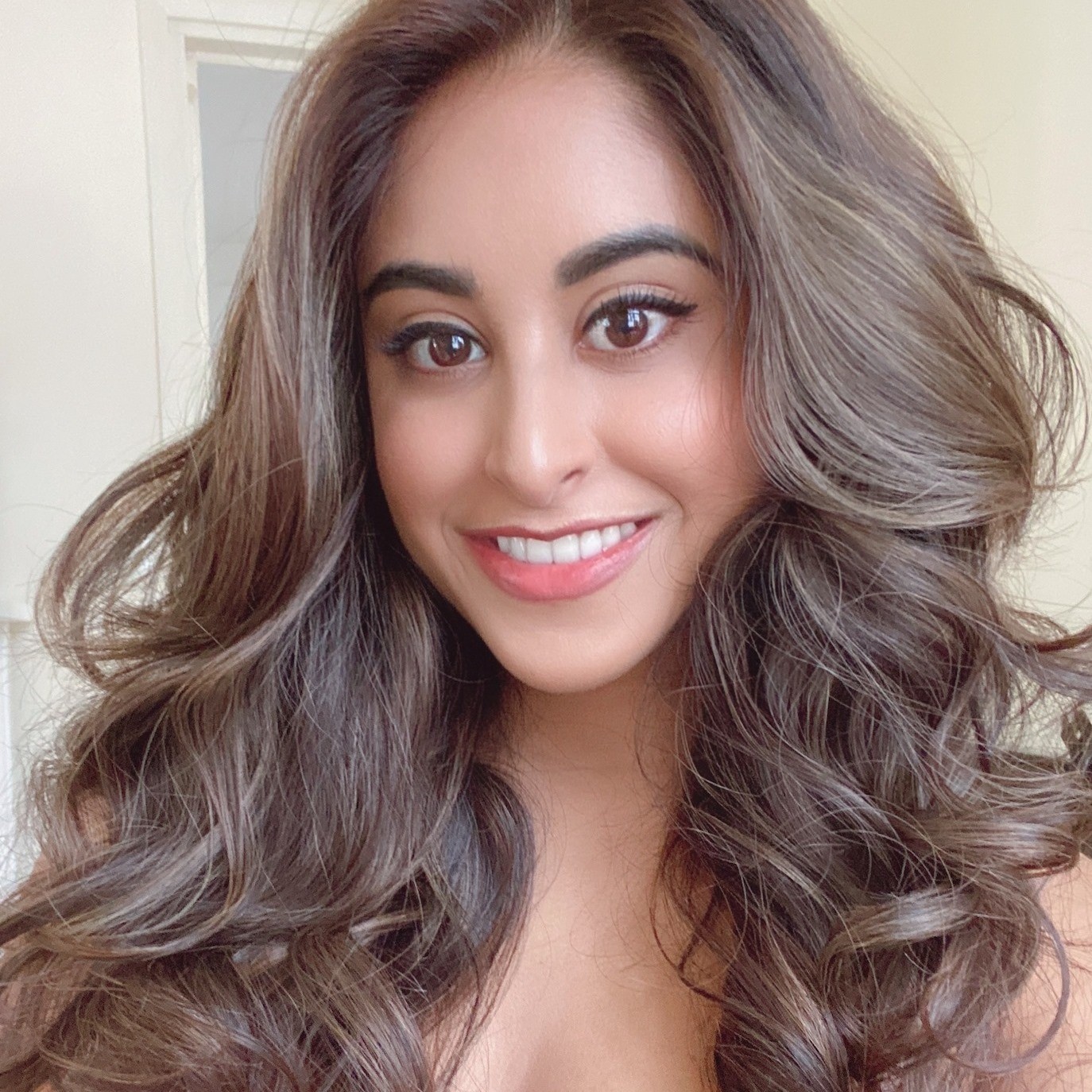 Image of a smiling woman with brown eyes and long brown softly curled hair. 