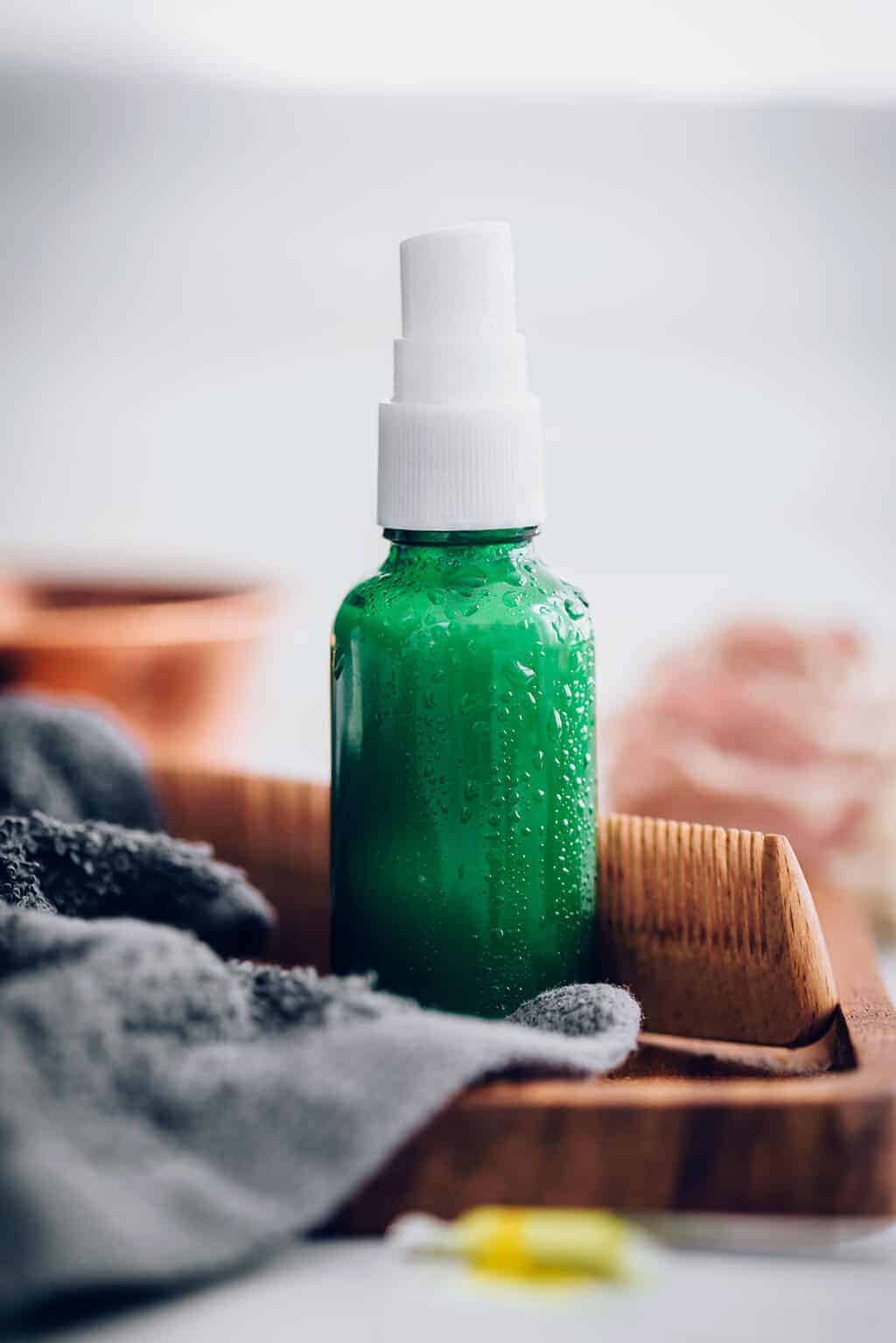 small green bottle with hair brush in background