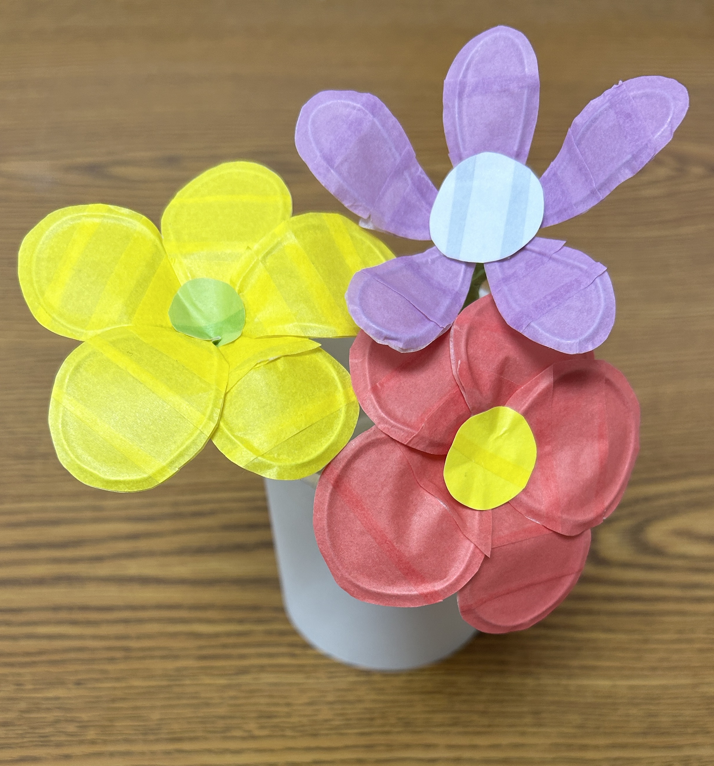 Three flowers made of washi tape in a white vase