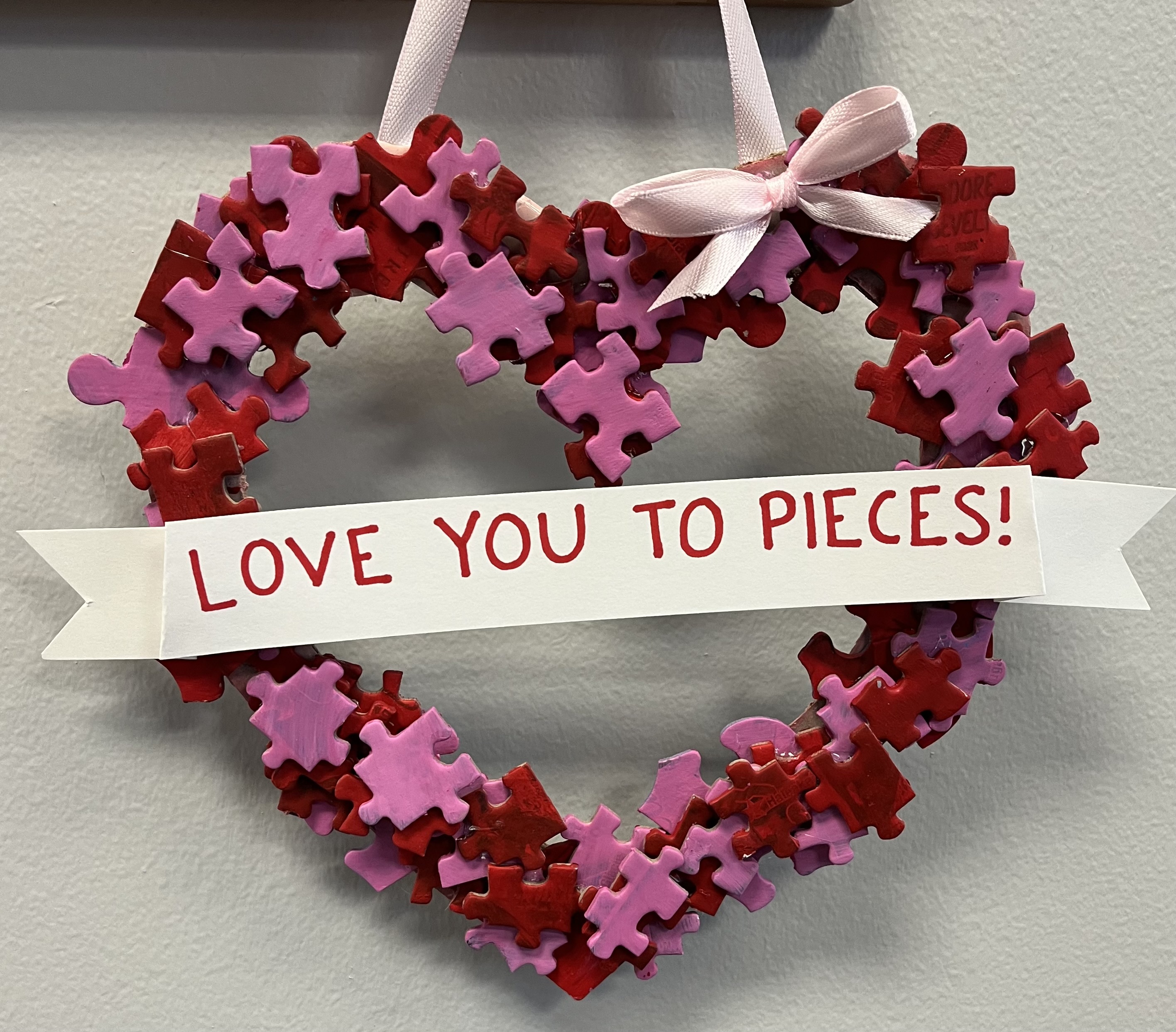 Wreath made out of puzzle pieces that says "Love You to Pieces"