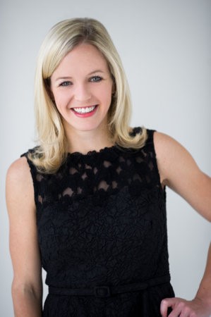 Image of a smiling blond woman in a black lace top. 