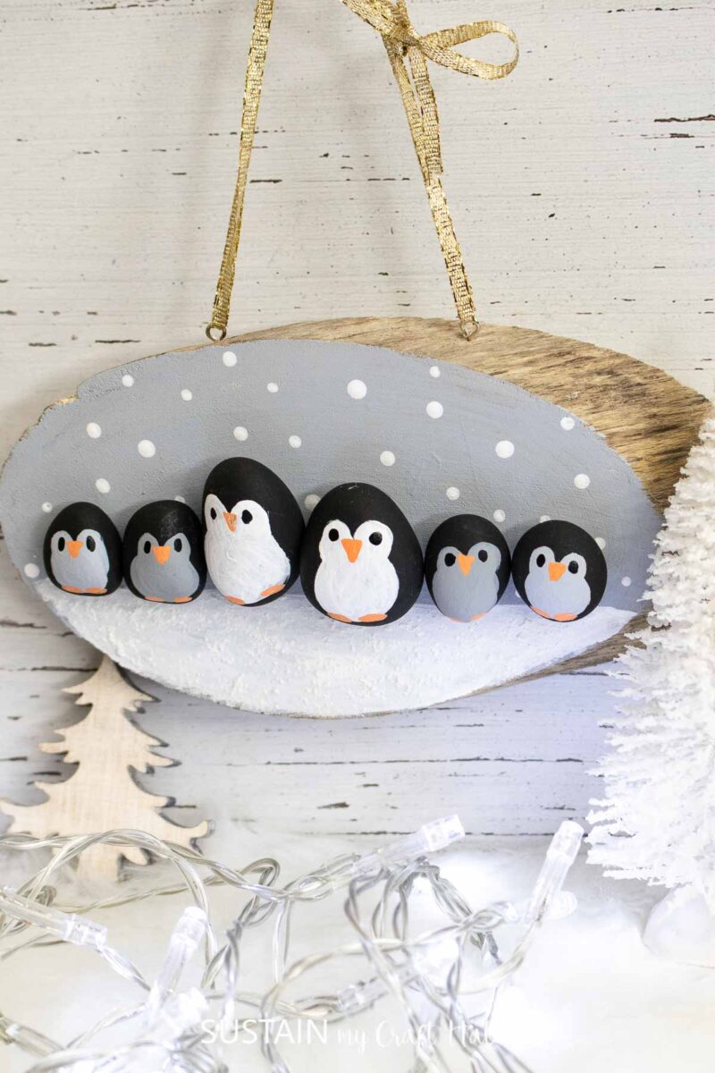painted rocks that look like penguins mounted on a piece of wood
