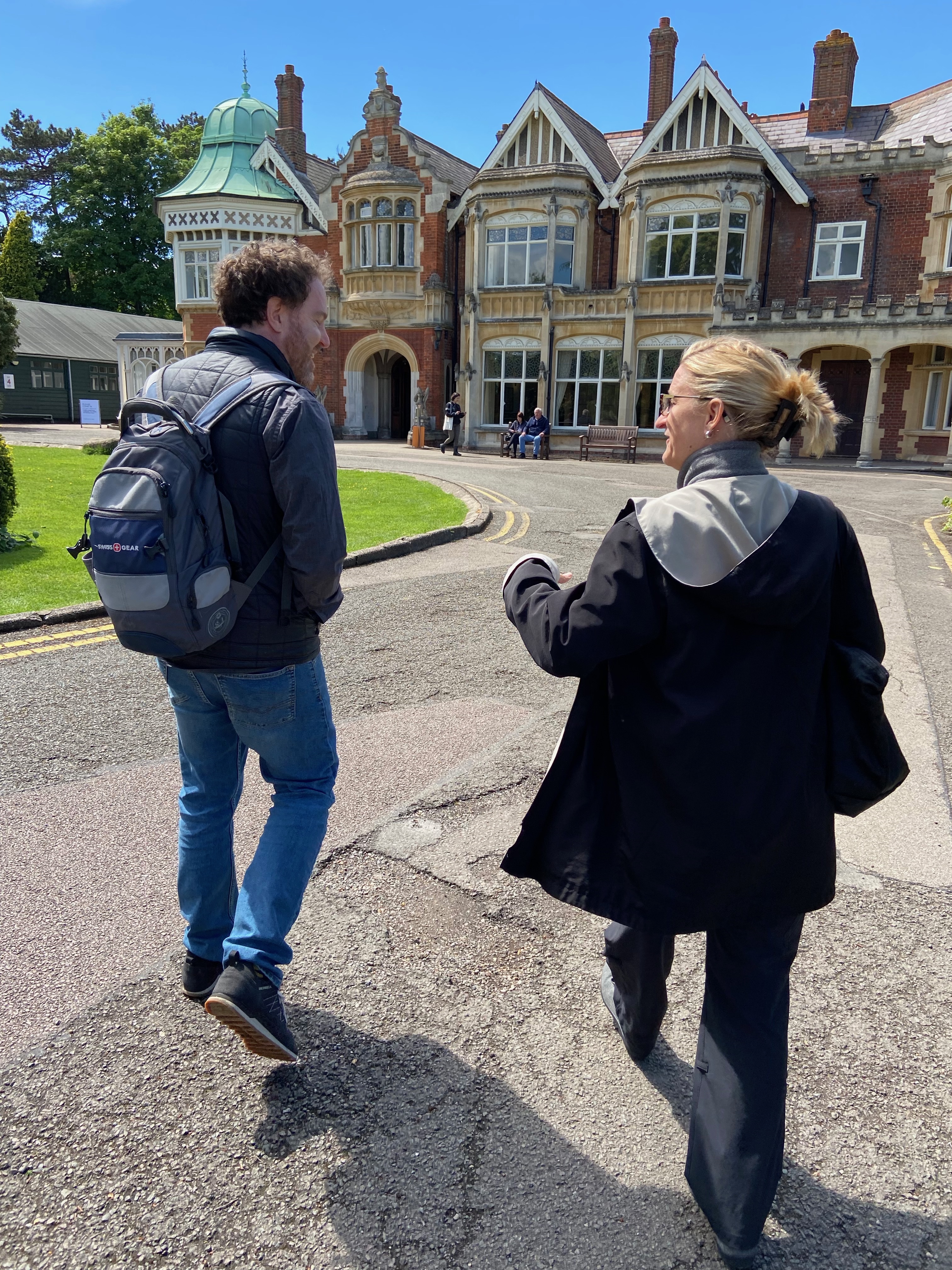 A man and woman walk towards an ornate historical brick building called Bletchley Park