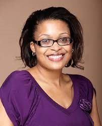 Image of a smiling African American woman wearing a purple shirt and glasses. 