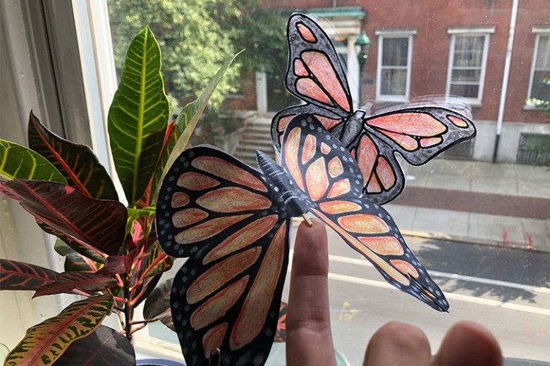 hand holding a balancing butterfly craft made out of paper