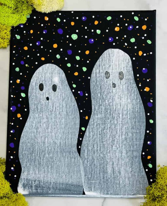 Image showing a black canvas with two ghosts and a colorful background painted on it.