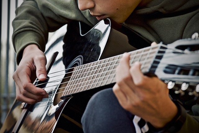 Medium close in picture of a teen playing acoustic guitar