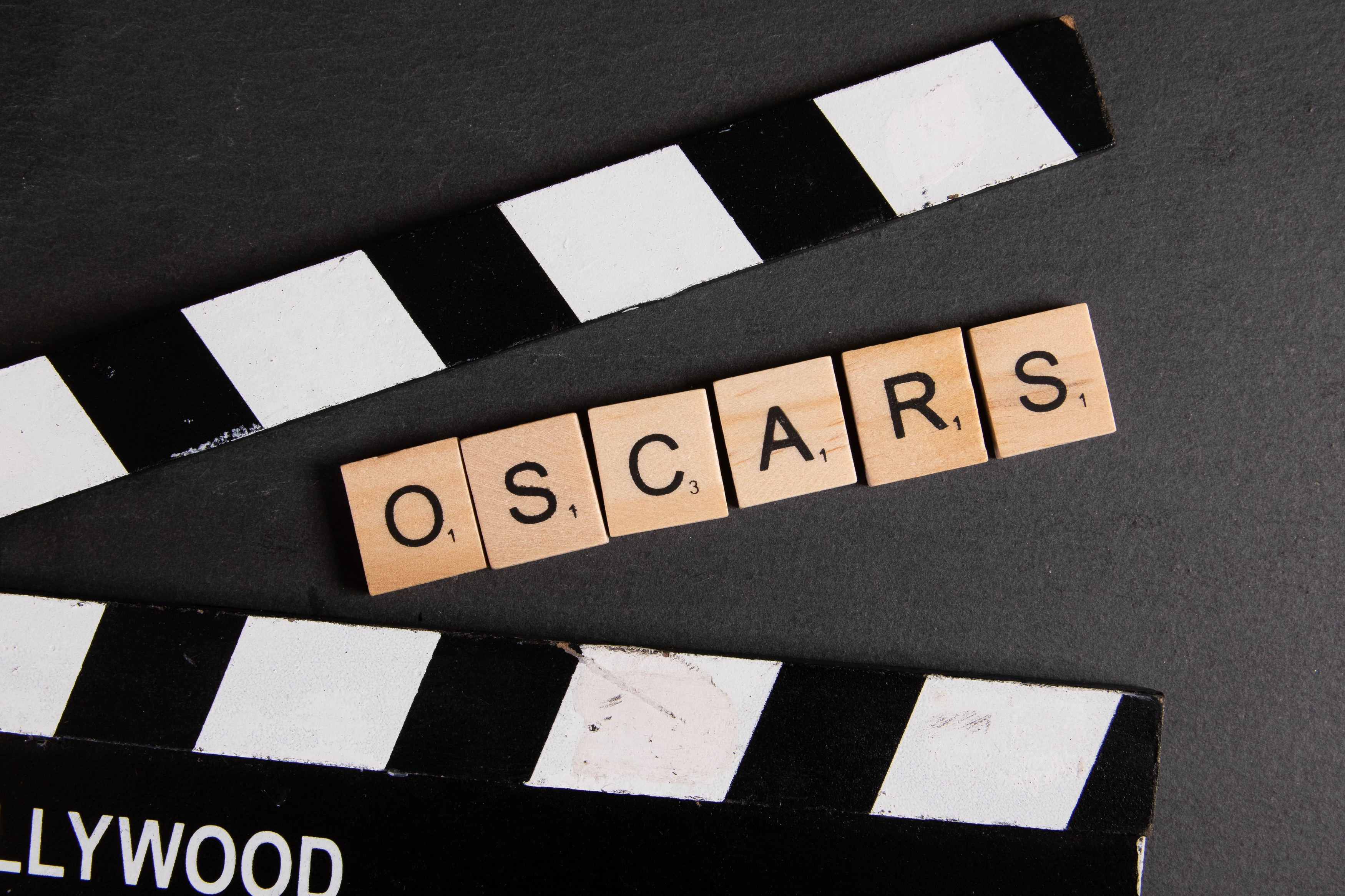 Movie film clap board with scrabble letters spelling out the word Oscars