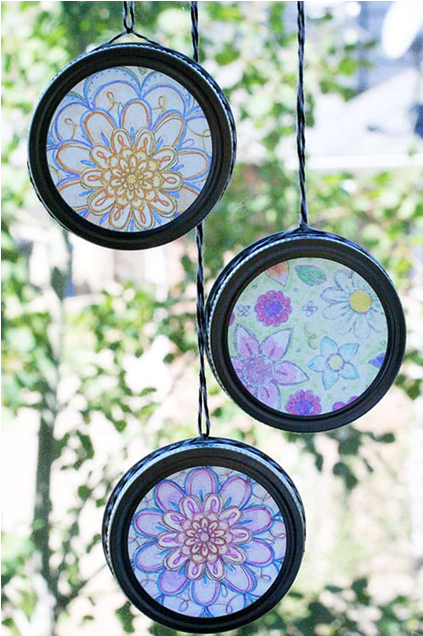 Suncatcher made using a coloring page and a mason jar lid and strung with yarn for hanging in the window.