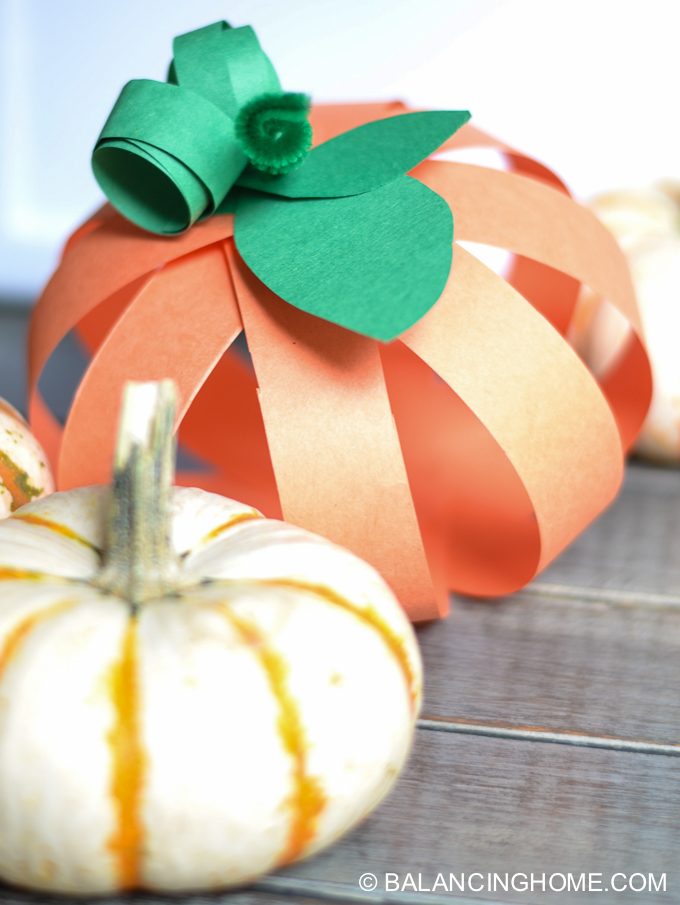 paper pumpkin next to a real pumpkin