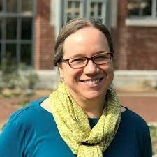 woman with glasses, green scarf, and blue blouse