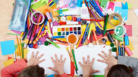 Kids sitting at table of art supplies