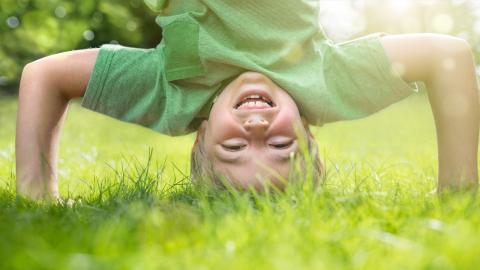 Child doing a headstand in grass