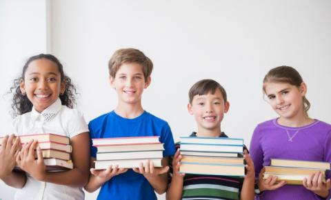 A group of tweens holding stacks of books