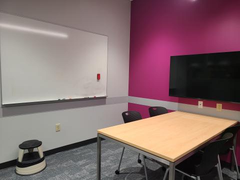 Study room with a table and chairs. There is a white board on one wall and a tv mounted on another wall. 